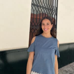 chica sonriendo con una camiseta azul de hombros descubiertos