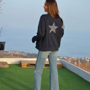 chica de espalda con un tejano azul y sudadera azul marino con estrella hecha de strass en espalda